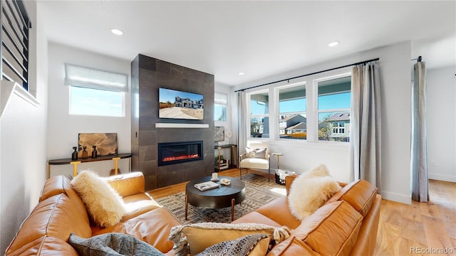 living room featuring a tiled fireplace and light hardwood / wood-style flooring