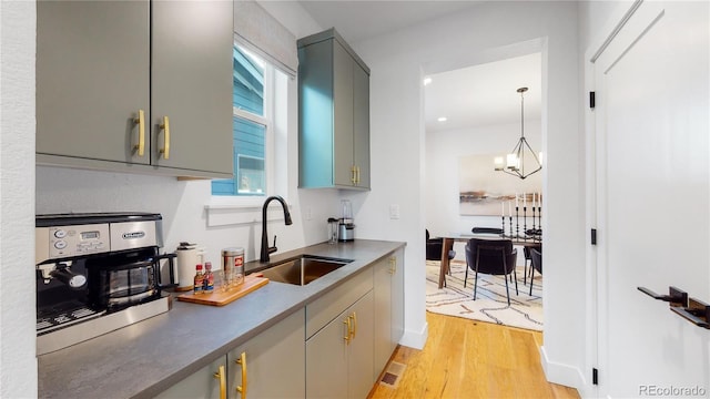 kitchen featuring decorative light fixtures, sink, gray cabinetry, a notable chandelier, and light wood-type flooring