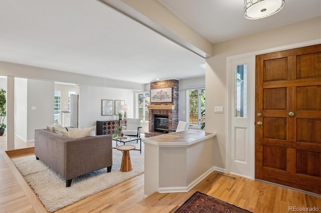 entryway with a fireplace, light wood-type flooring, and baseboards