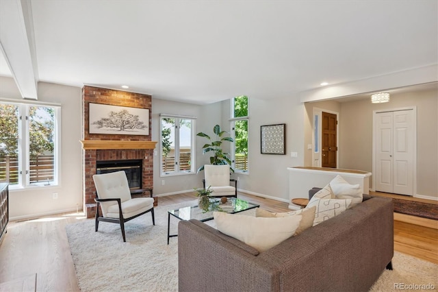 living area featuring light wood-type flooring, a brick fireplace, baseboards, and recessed lighting