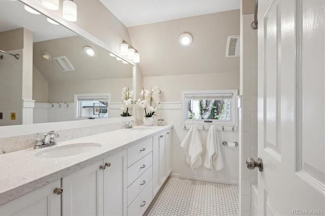 full bath with a shower, double vanity, tile patterned floors, and a wainscoted wall