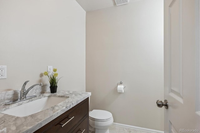 bathroom with toilet, vanity, and baseboards