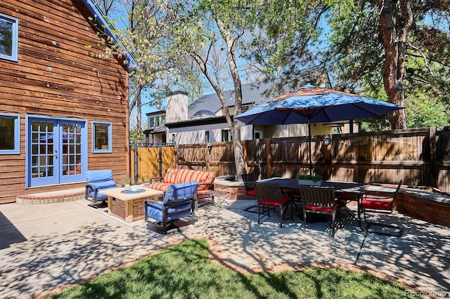 view of patio featuring a fire pit, french doors, fence, and outdoor dining area