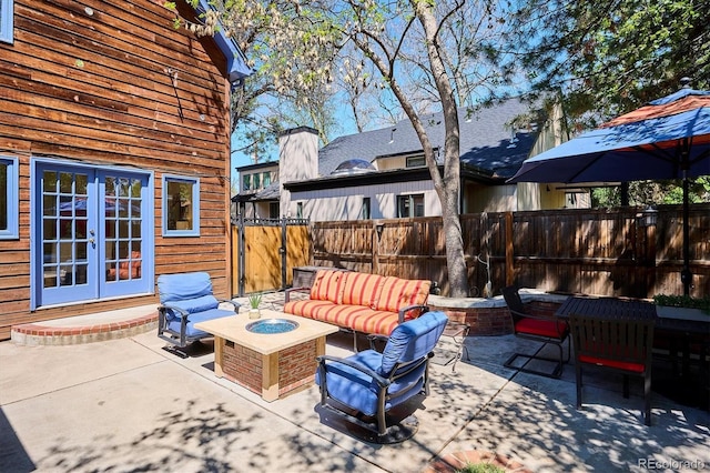 view of patio / terrace with french doors, an outdoor living space with a fire pit, and fence