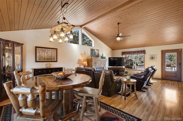 dining area with wood ceiling, vaulted ceiling, light hardwood / wood-style floors, and a stone fireplace