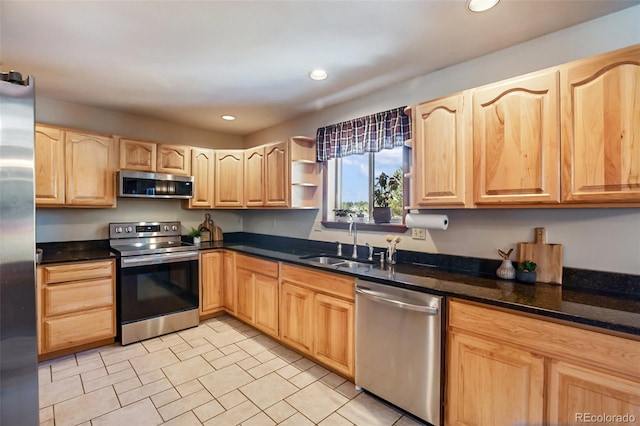 kitchen with sink, light brown cabinets, dark stone counters, and appliances with stainless steel finishes