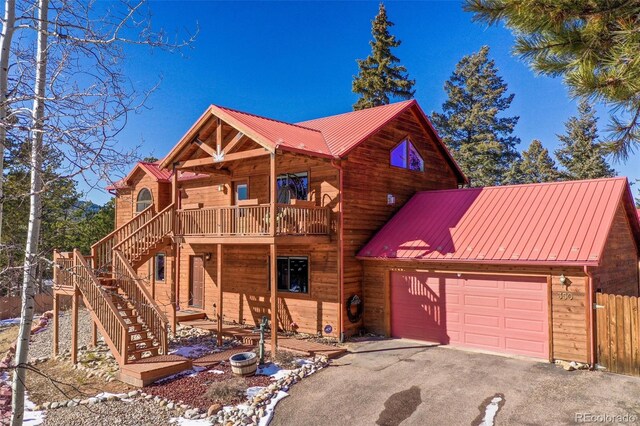 350 Panther Ct, Woodland Park, CO 80863 - view of front facade featuring driveway, fence, metal roof, an attached garage, and stairs