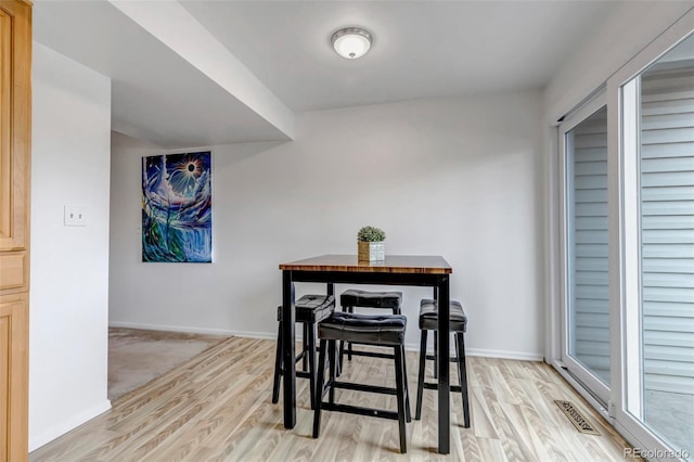 dining room with light wood-type flooring, baseboards, and visible vents