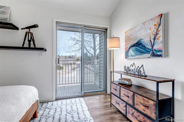 bedroom with lofted ceiling, wood finished floors, visible vents, and access to exterior