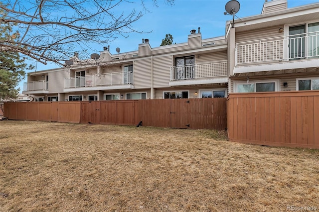 back of property with a yard, a chimney, and fence