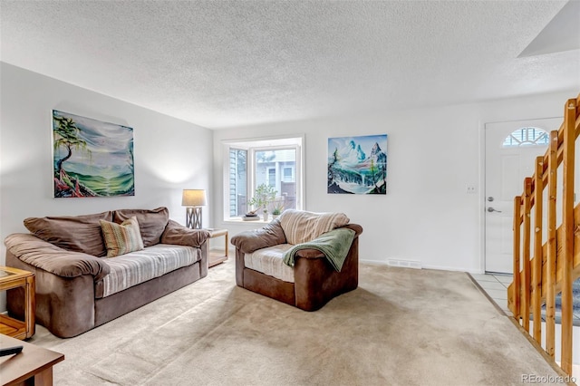 living area with visible vents, stairway, light carpet, a textured ceiling, and baseboards