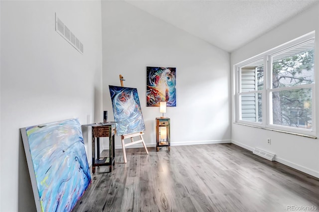 living area featuring vaulted ceiling, wood finished floors, visible vents, and baseboards