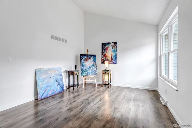 sitting room with vaulted ceiling, wood finished floors, visible vents, and baseboards