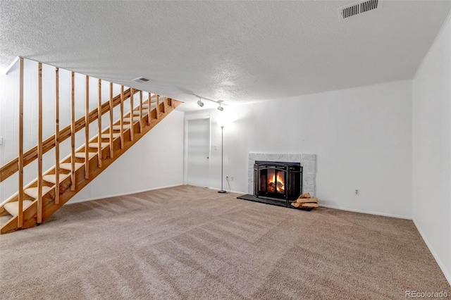 unfurnished living room with stairway, a tiled fireplace, carpet flooring, and visible vents