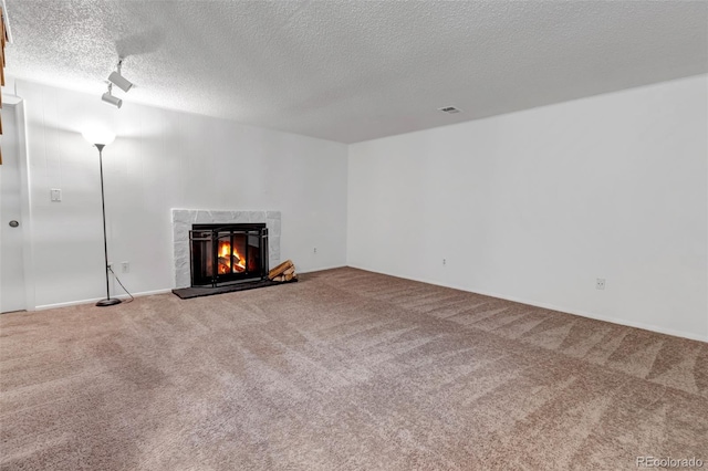 unfurnished living room featuring a textured ceiling, visible vents, carpet flooring, and a high end fireplace