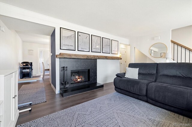 living area with stairs, a glass covered fireplace, and wood finished floors