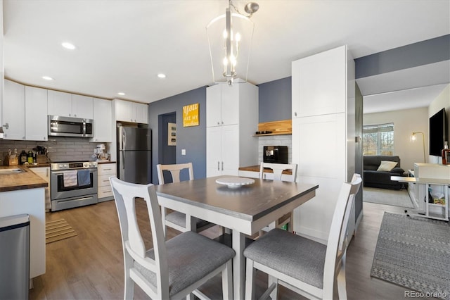 dining room with light wood-style flooring, a fireplace, and recessed lighting