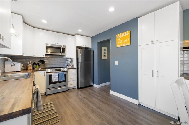 kitchen with stainless steel appliances, butcher block counters, dark wood-type flooring, and a sink