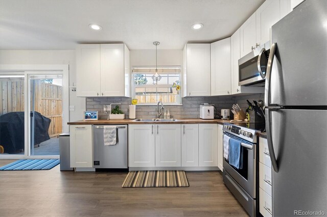 kitchen featuring stainless steel appliances, butcher block countertops, a sink, and dark wood-style floors