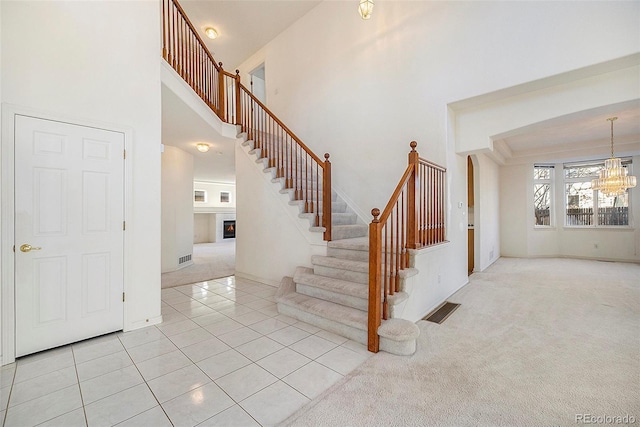 staircase featuring a towering ceiling, carpet, and a chandelier