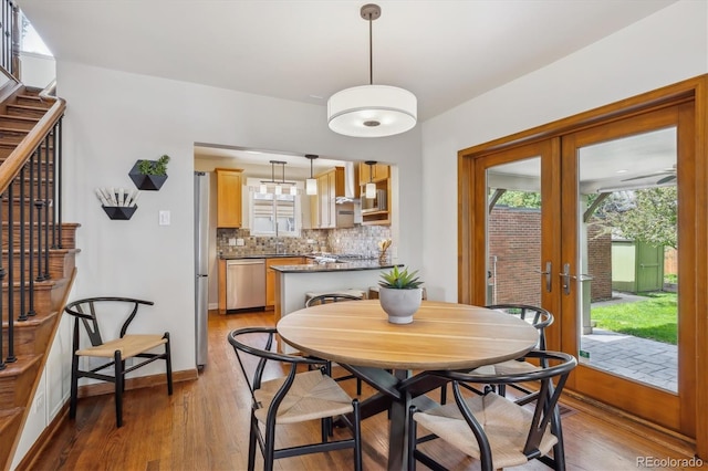 dining space with light wood-style flooring, french doors, and stairs
