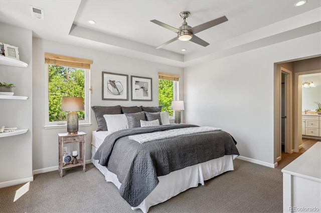 bedroom featuring carpet, baseboards, a tray ceiling, recessed lighting, and ensuite bathroom