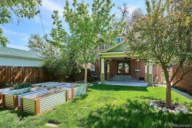 view of yard with a vegetable garden, french doors, and ceiling fan