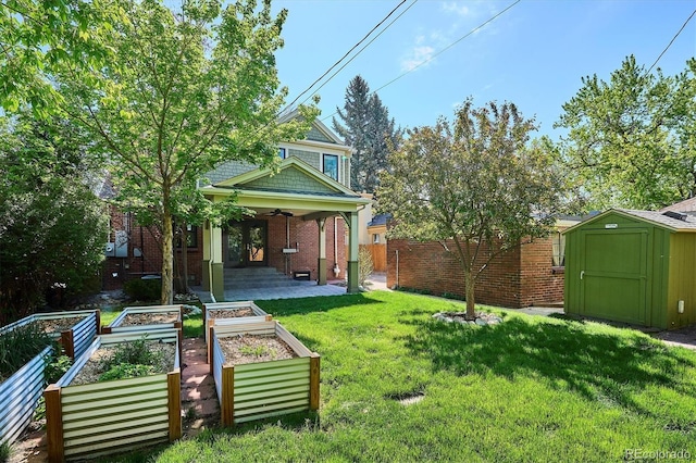 view of yard with a vegetable garden, a storage unit, ceiling fan, and an outbuilding