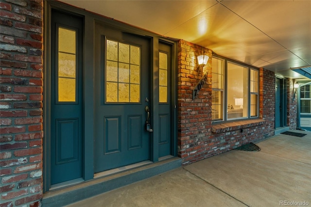 doorway to property featuring brick siding and covered porch