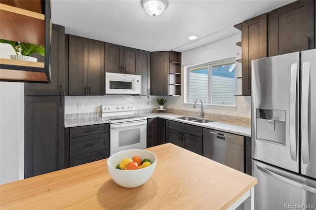 kitchen featuring open shelves, dark brown cabinetry, light countertops, stainless steel appliances, and a sink