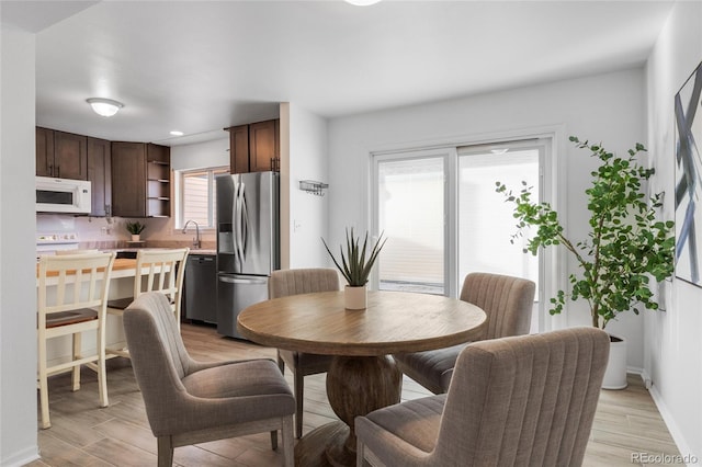 dining space with baseboards and light wood-type flooring