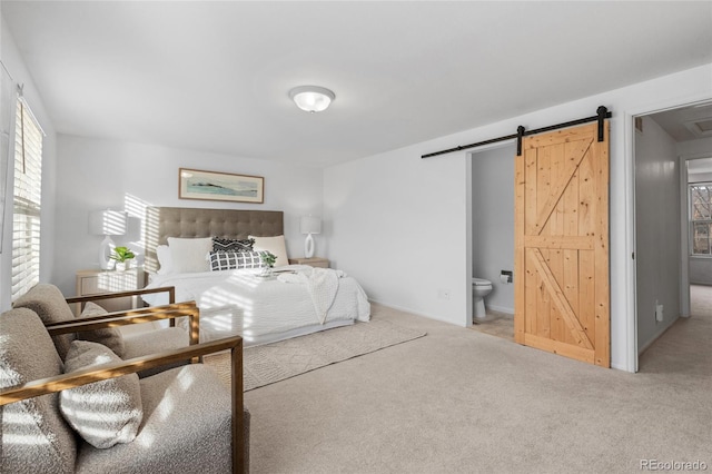 carpeted bedroom with ensuite bath and a barn door