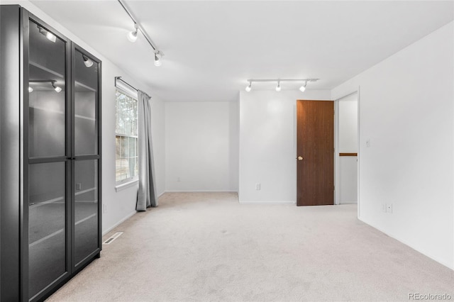 carpeted spare room with track lighting and visible vents