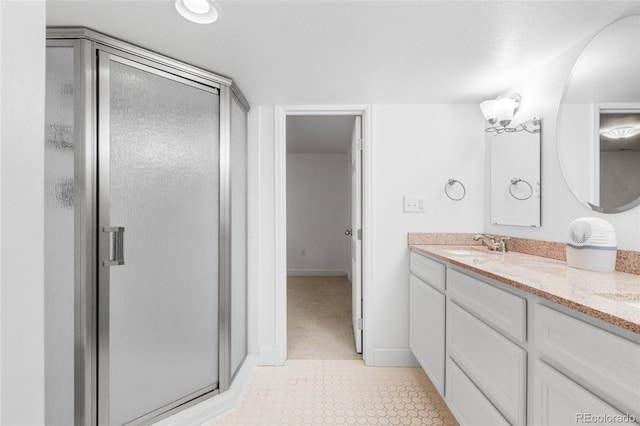 full bath featuring double vanity, a shower stall, baseboards, and a sink