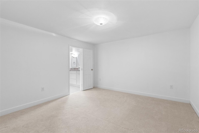 unfurnished room featuring baseboards and light carpet