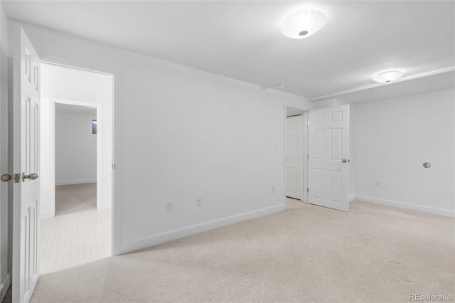 spare room featuring baseboards and light colored carpet