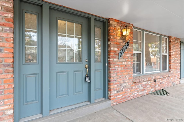 entrance to property with brick siding and a porch