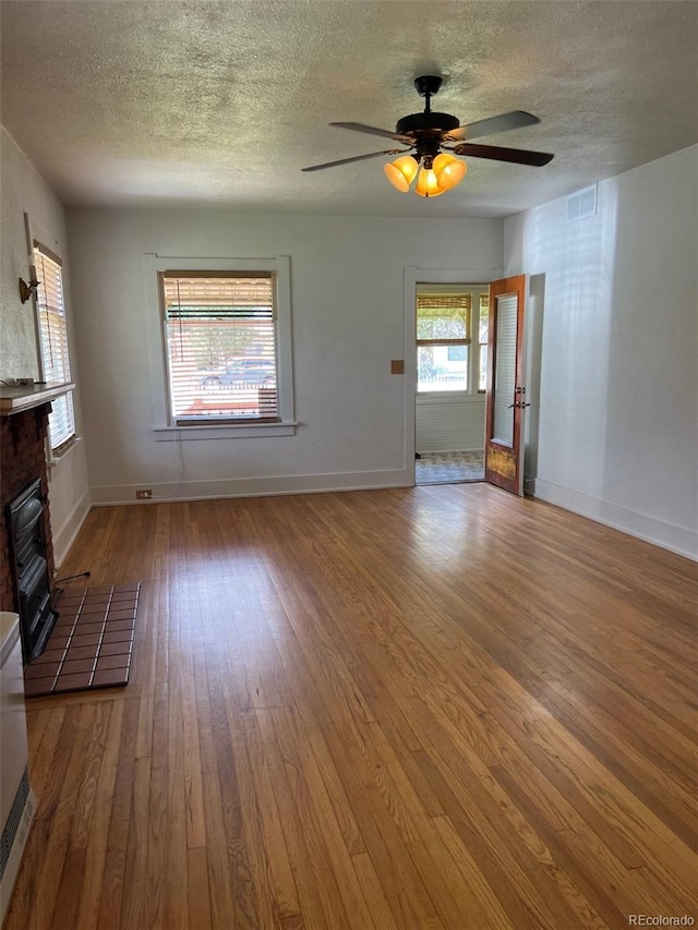 40 Bronk St, Monte Vista, CO 81144 - unfurnished living room featuring a textured ceiling, a tile fireplace, wood finished floors, and ceiling fan