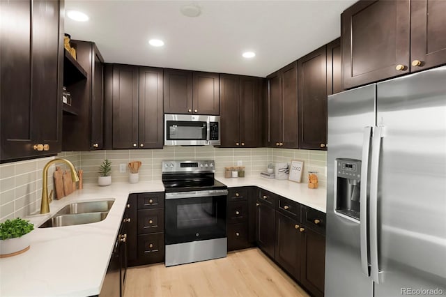 14544 March Dr, Denver, CO 80239 - kitchen featuring appliances with stainless steel finishes, light wood finished floors, tasteful backsplash, dark brown cabinets, and recessed lighting