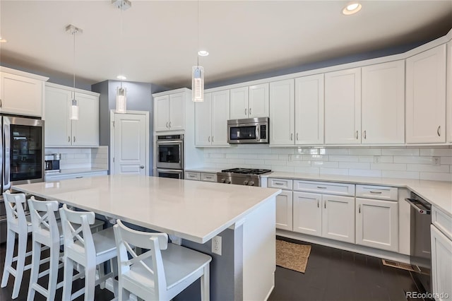 kitchen featuring pendant lighting, a breakfast bar, appliances with stainless steel finishes, a center island, and white cabinets