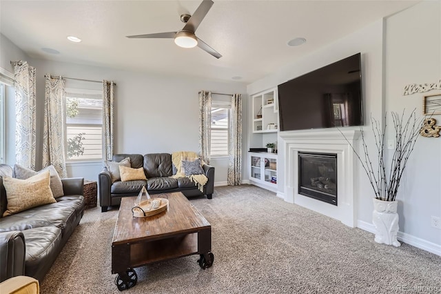 living room featuring ceiling fan, carpet floors, built in features, and a healthy amount of sunlight