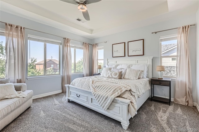 carpeted bedroom with ceiling fan and a tray ceiling