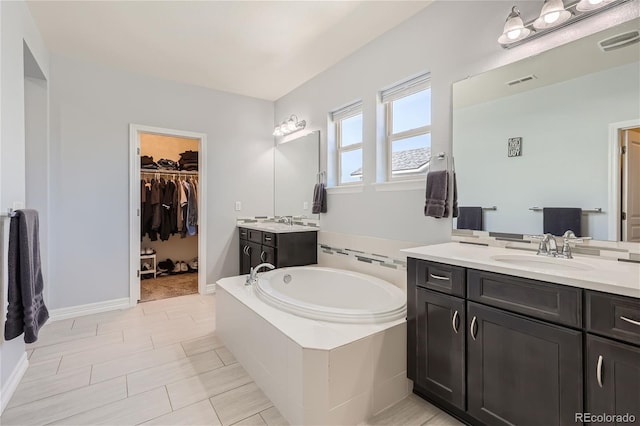 bathroom featuring a relaxing tiled tub, tile patterned floors, and vanity