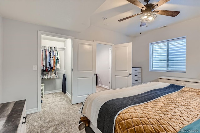 carpeted bedroom featuring a walk in closet, a closet, and ceiling fan