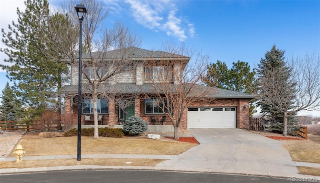 traditional-style house featuring a garage, brick siding, concrete driveway, and fence