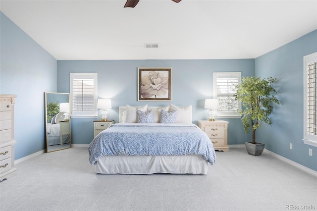 carpeted bedroom with visible vents, multiple windows, a ceiling fan, and baseboards