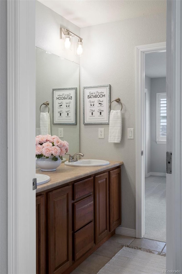 bathroom with tile patterned floors, a sink, baseboards, and double vanity