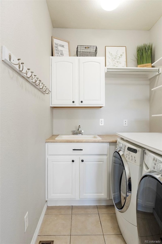 clothes washing area featuring light tile patterned floors, baseboards, cabinet space, separate washer and dryer, and a sink