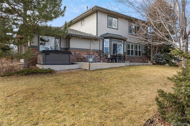 rear view of house with a yard, a patio, and brick siding