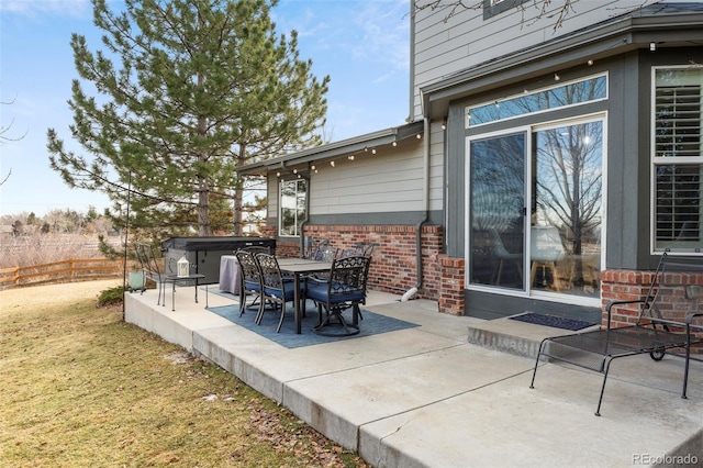 view of patio featuring outdoor dining area, fence, and a hot tub